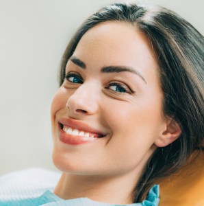 Photo: Female patient in dental chair, showing off her great smile